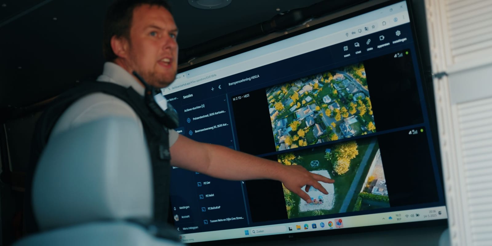 A Belgian police officer pointing at two simultaneous drone feeds in the AirHub live operations view during a disaster exercise