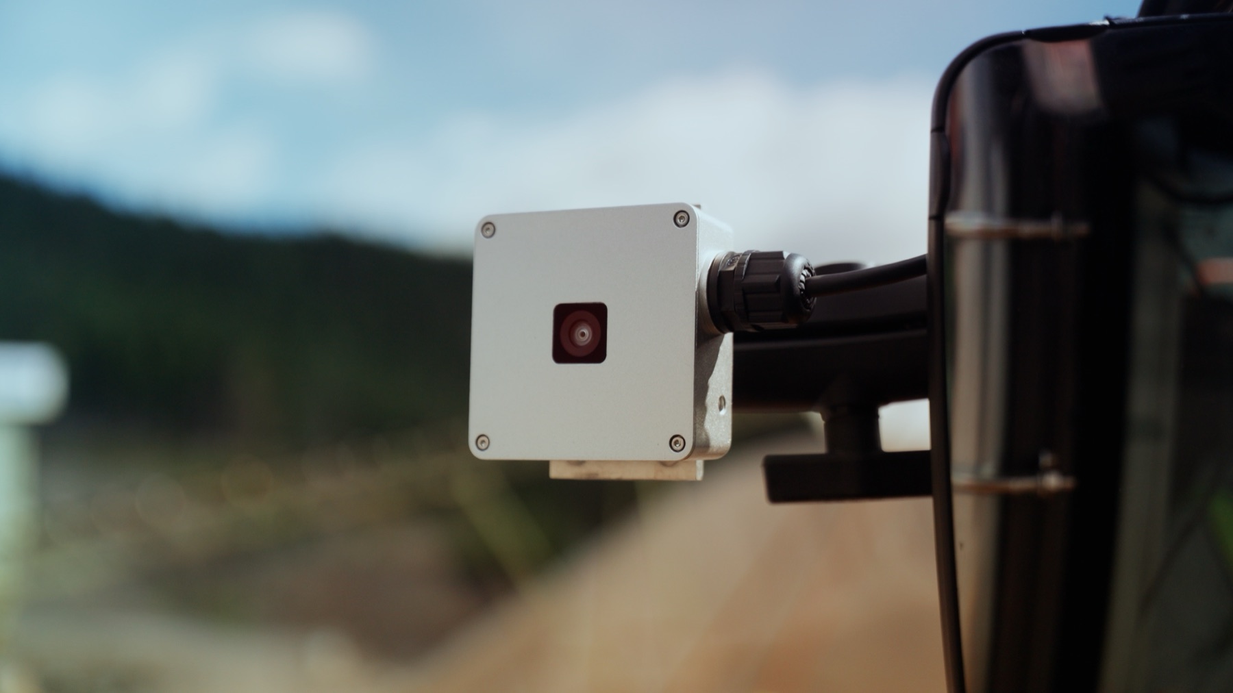 Close-up of a HIVE sensor unit mounted on the wheel loader, with the quarry out of focus behind it