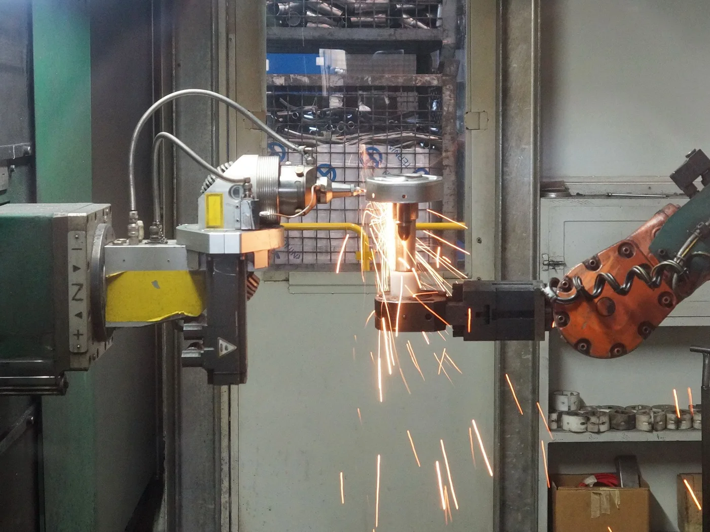 A robotic welding cell throwing sparks inside a production facility
