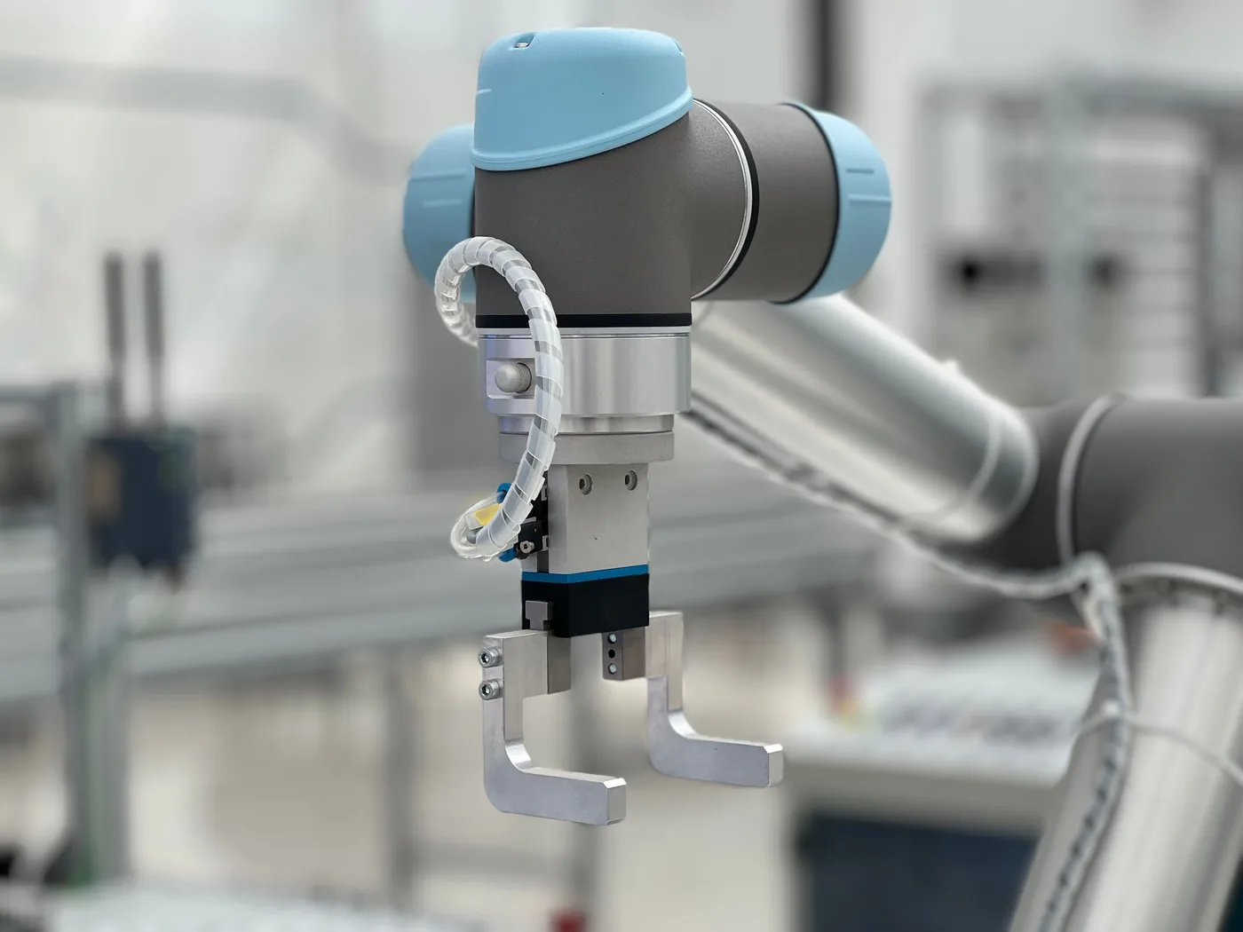 A collaborative robot arm with a gripper working on a production line