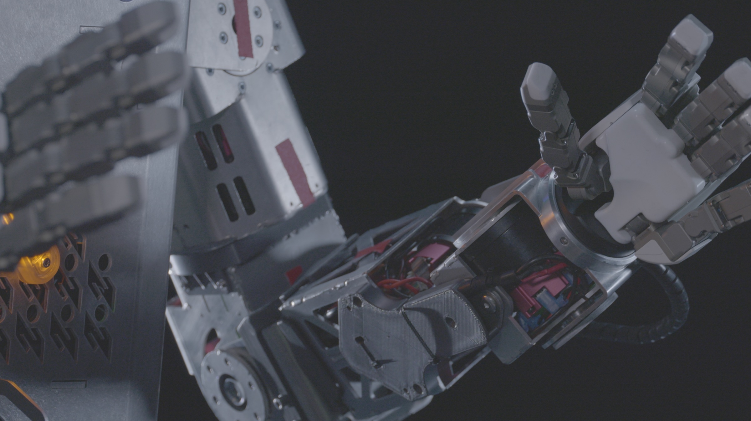 Close-up of the hands and forearms of Roger, the Minerva Humanoids robot, showing the exposed actuators and articulated fingers against a dark background