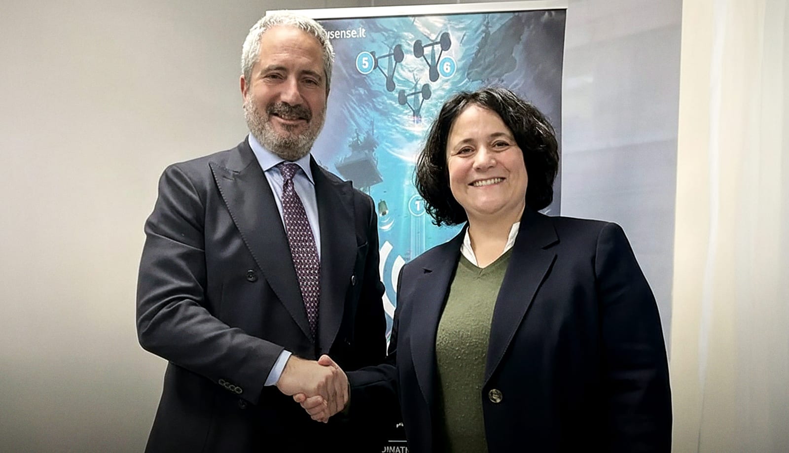 Chiara Petrioli shaking hands with a Fincantieri executive in front of a WSense banner